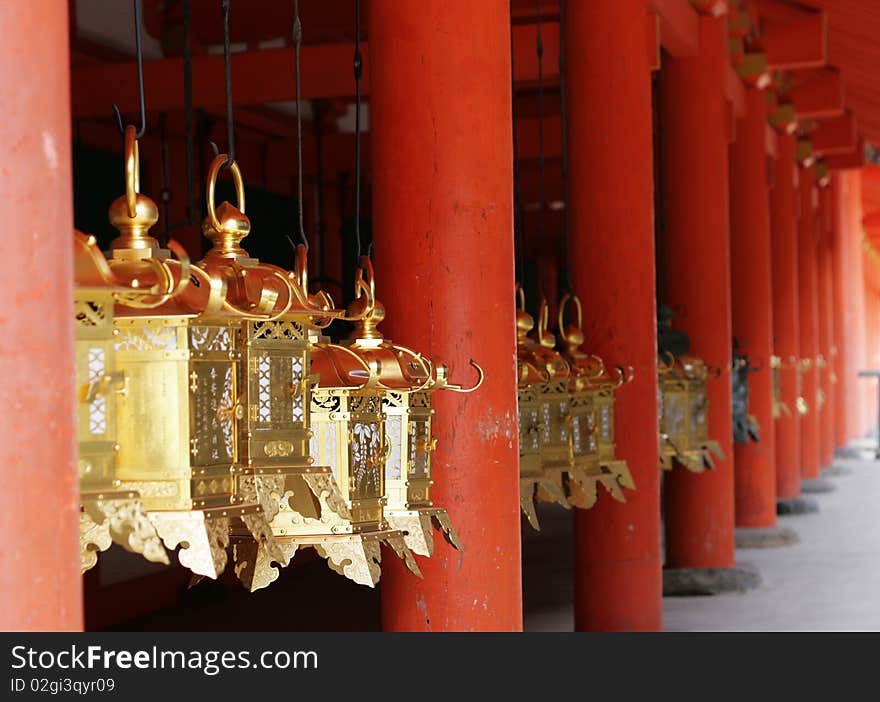 Golden Lanterns hang between red pillars at a Shinto Temple in Nara, Japan's ancient capital. Golden Lanterns hang between red pillars at a Shinto Temple in Nara, Japan's ancient capital.