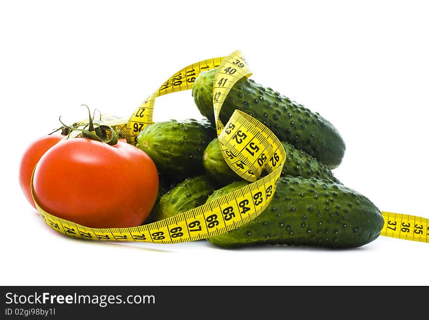 Tomatoes and cucumbers with yellow measuring tape isolated on white. Tomatoes and cucumbers with yellow measuring tape isolated on white