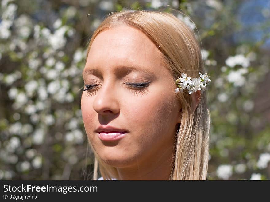 Blond girl in front of blossomed tree on early spring