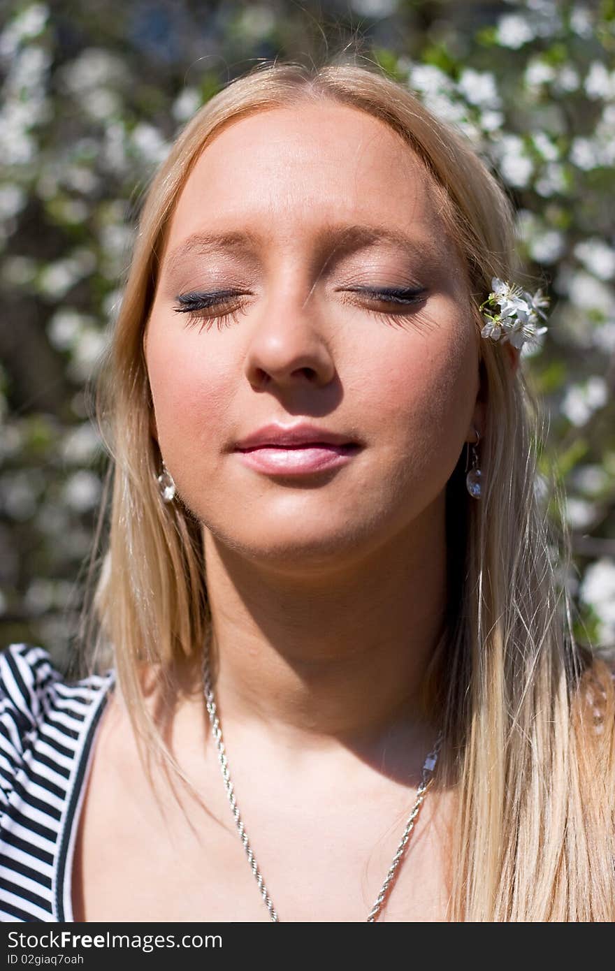 Blond girl in front of blossomed tree on early spring