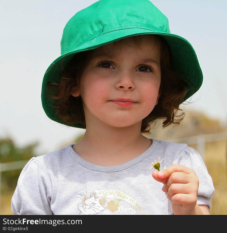 Little girl wearing a hat and holding a flower. Little girl wearing a hat and holding a flower