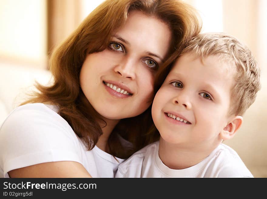 Happy young mother hugging her little son at home