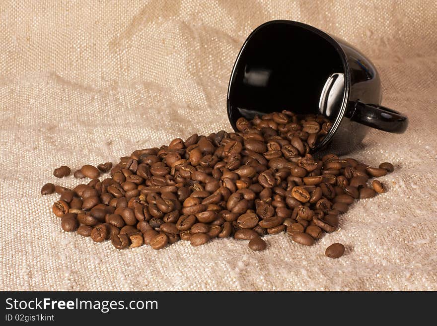 Mug with coffee beans on the rustic canvas