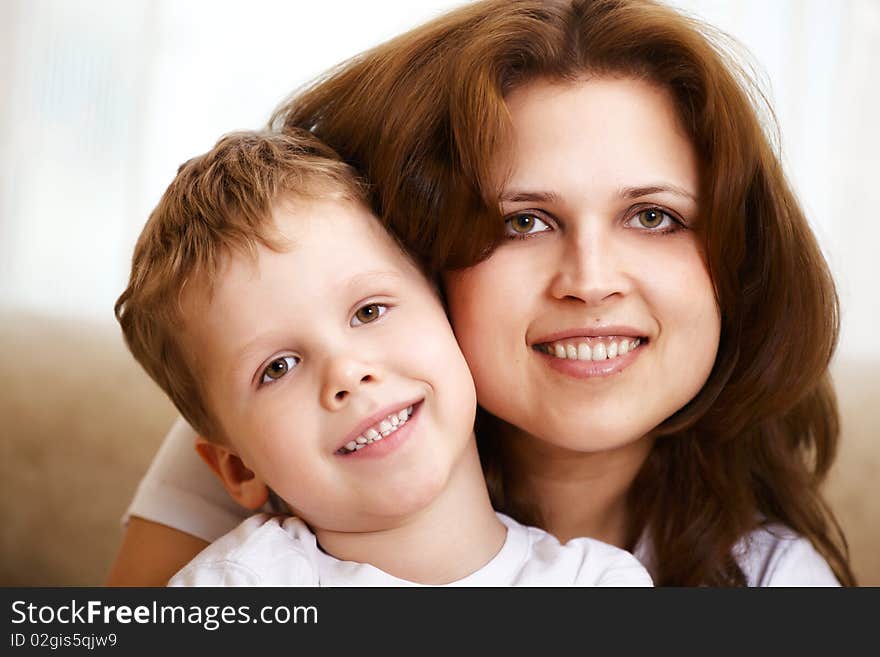 Happy young mother hugging her little son indoor