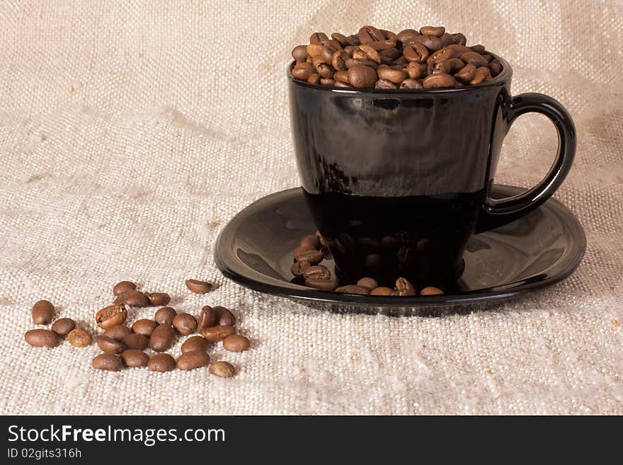 Mug with coffee beans on the rustic canvas