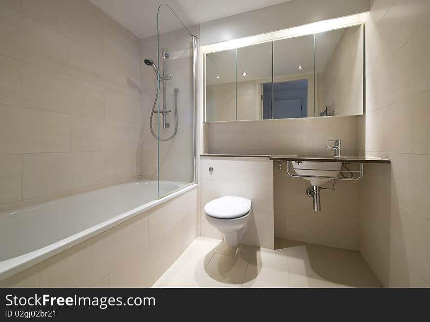 Modern bathroom with a designer wash basin and bath tub in beige