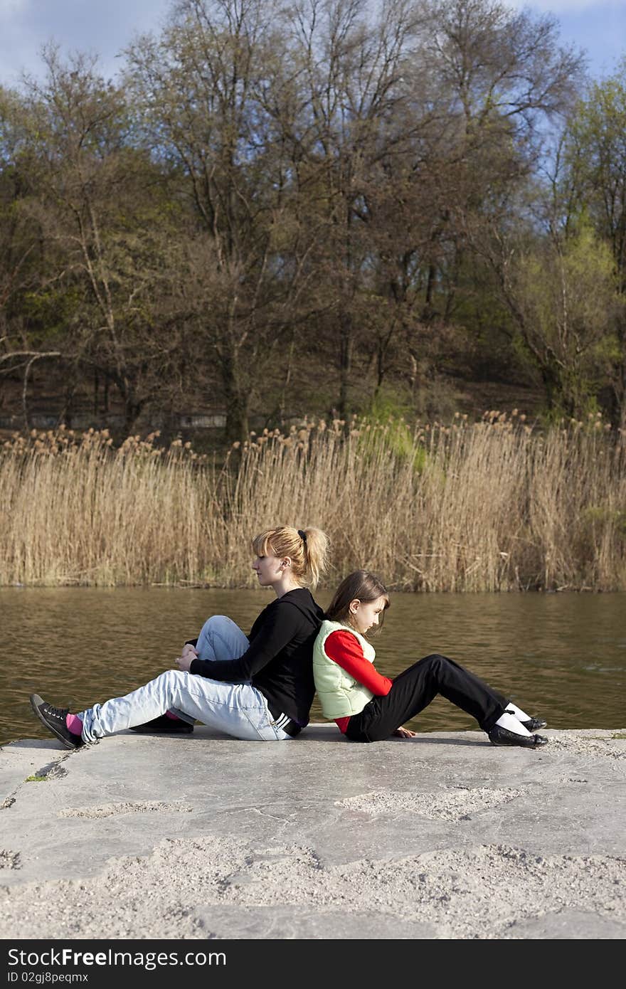 Cute girl with woman sitting near a lake. Cute girl with woman sitting near a lake