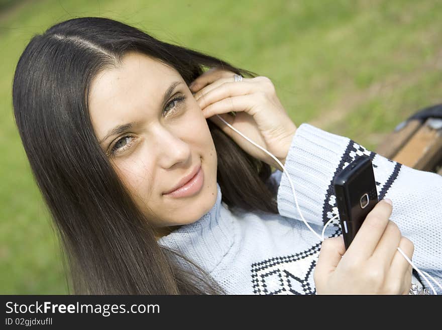 Beautiful girl in a park listening to music from your mobile phone