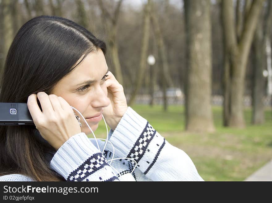 Beautiful girl in a park listening to music from your mobile phone