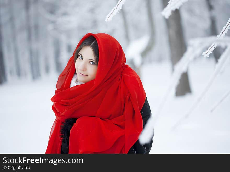 Beautiful girl in winter forest in red