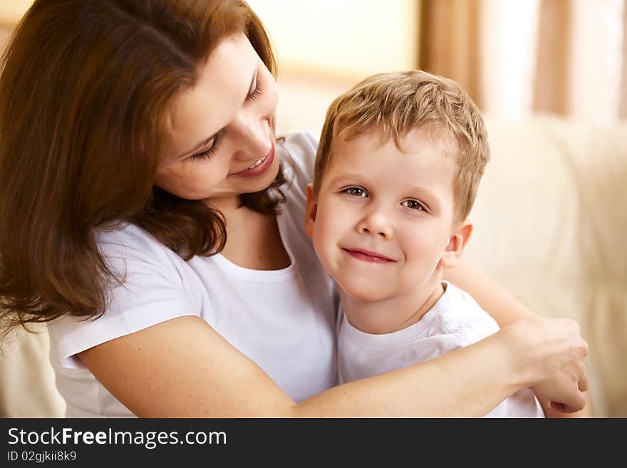 Happy young mother hugging her little son indoor