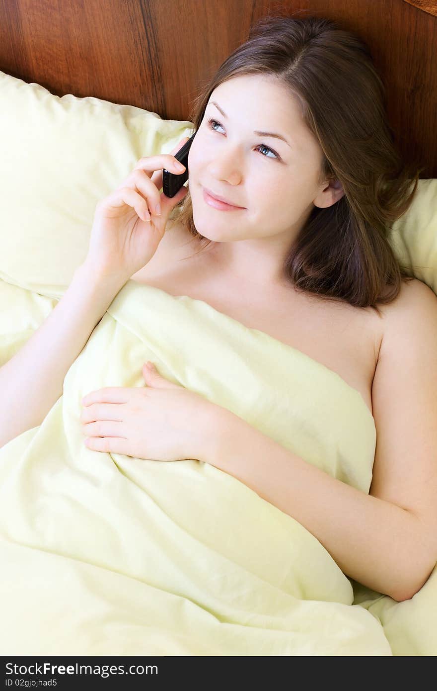 Young beautiful woman with mobile phone in the bed. Young beautiful woman with mobile phone in the bed