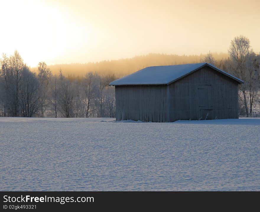 Old barn in cold winter sunrise