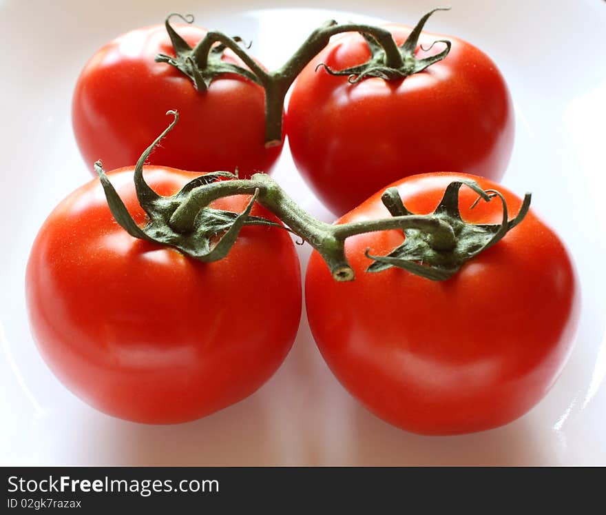 Two pairs of ripe red tomatoes on the vine. Two pairs of ripe red tomatoes on the vine.