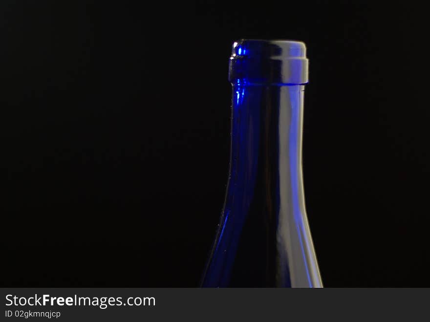 The neck of a blue glass botlle shot against a black background. The neck of a blue glass botlle shot against a black background.