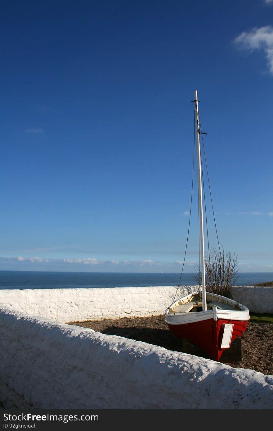 Solitary boat within a garden wall on bright sunny day