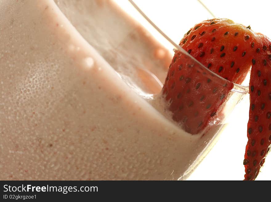 Close-up of strawberry smoothie with fresh strawberry on rim of glass