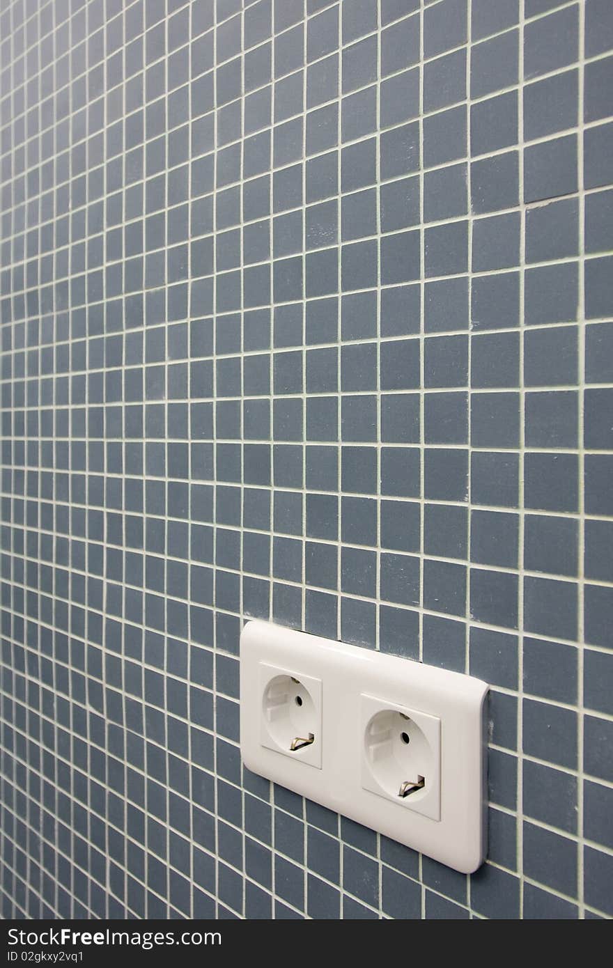 Detail of a double power European electric plug on tiled wall