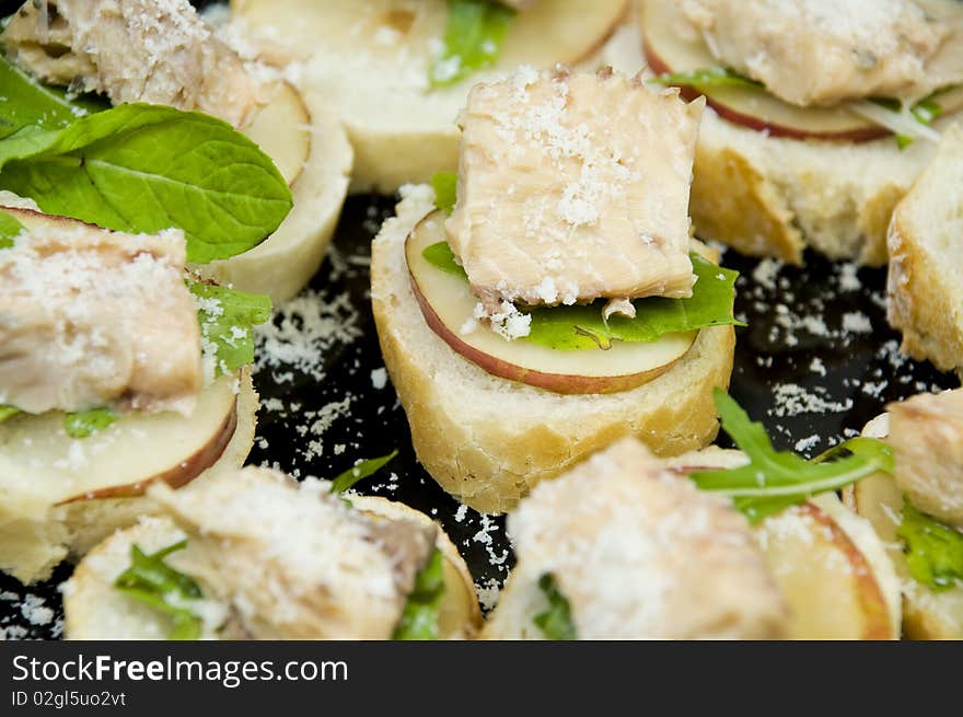 Closeup on freshly made salmon canapes with rucola, pear and parmesan. Closeup on freshly made salmon canapes with rucola, pear and parmesan