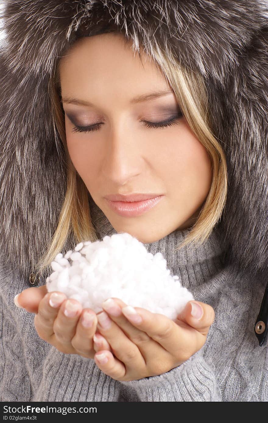 Portrait of a young and attractive blond with a winter hat holding snow in her hands. Portrait of a young and attractive blond with a winter hat holding snow in her hands.