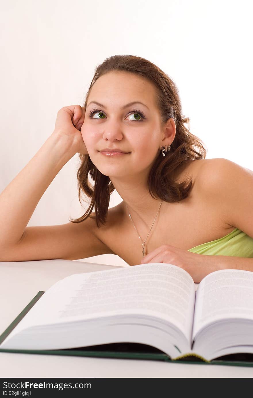 Pretty girl sitting at a table with a book on white background. Pretty girl sitting at a table with a book on white background