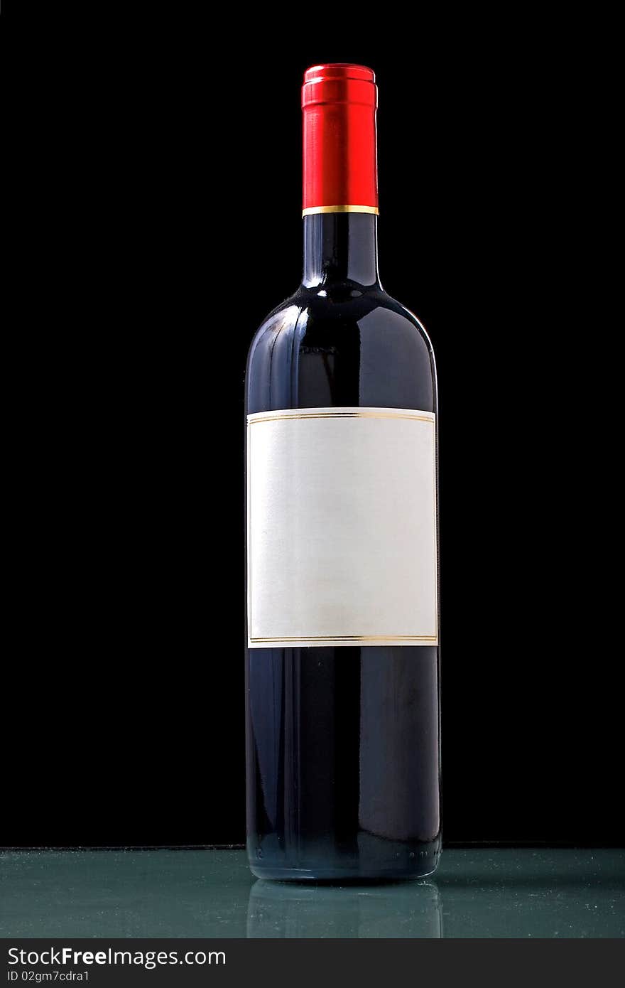 Bottle of red with a white textured label and red cap on black background with copy space for your text. Bottle of red with a white textured label and red cap on black background with copy space for your text