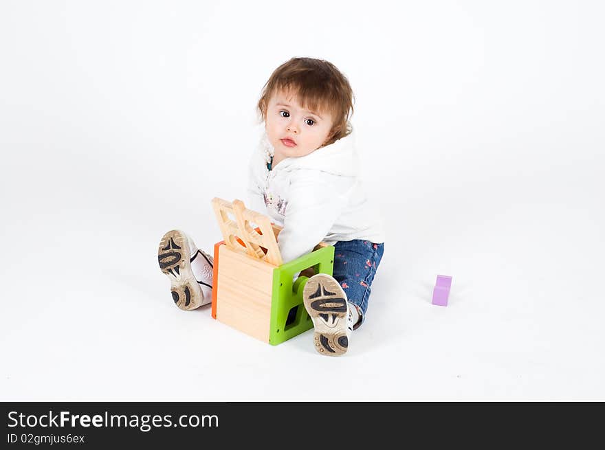 Serious little girl playing with wooden puzzle cub