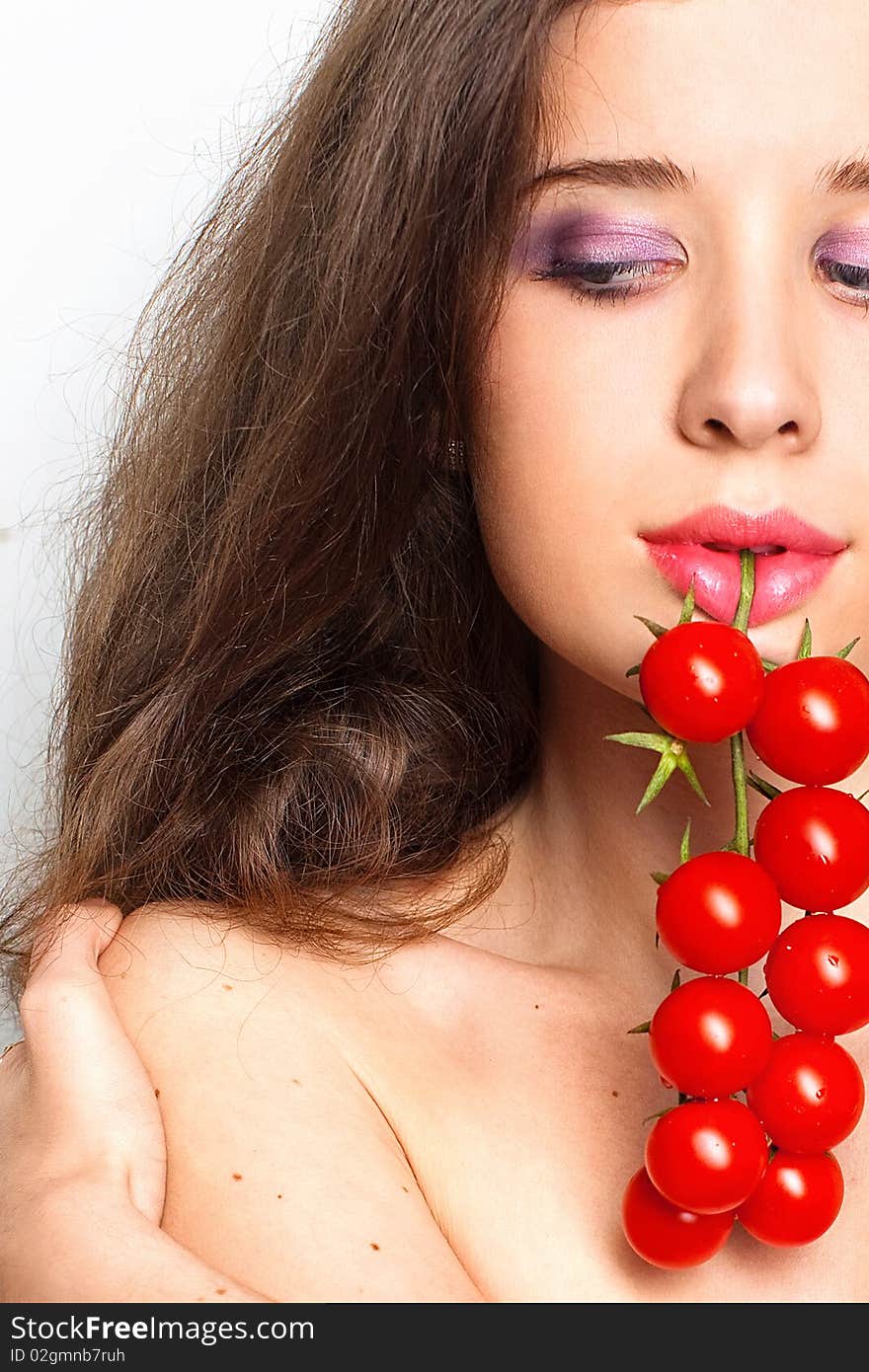 Young sexy girl with cherry tomatoes in her mouth