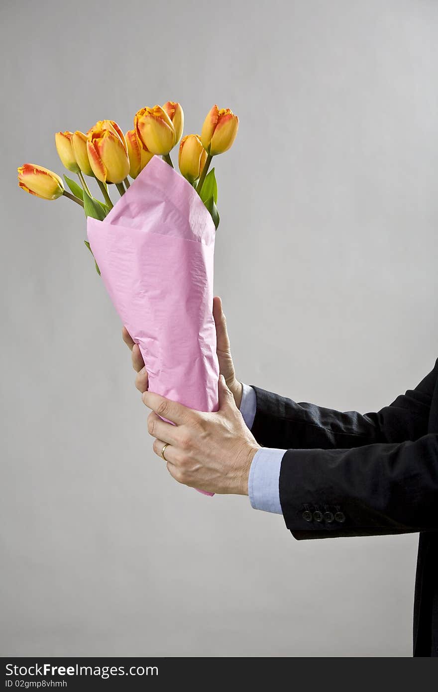 Man's two hands holding a bouquet of orange tulips. Man's two hands holding a bouquet of orange tulips