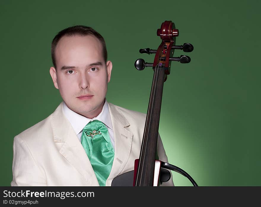 Portrait of young man with electic cello on green background. Portrait of young man with electic cello on green background