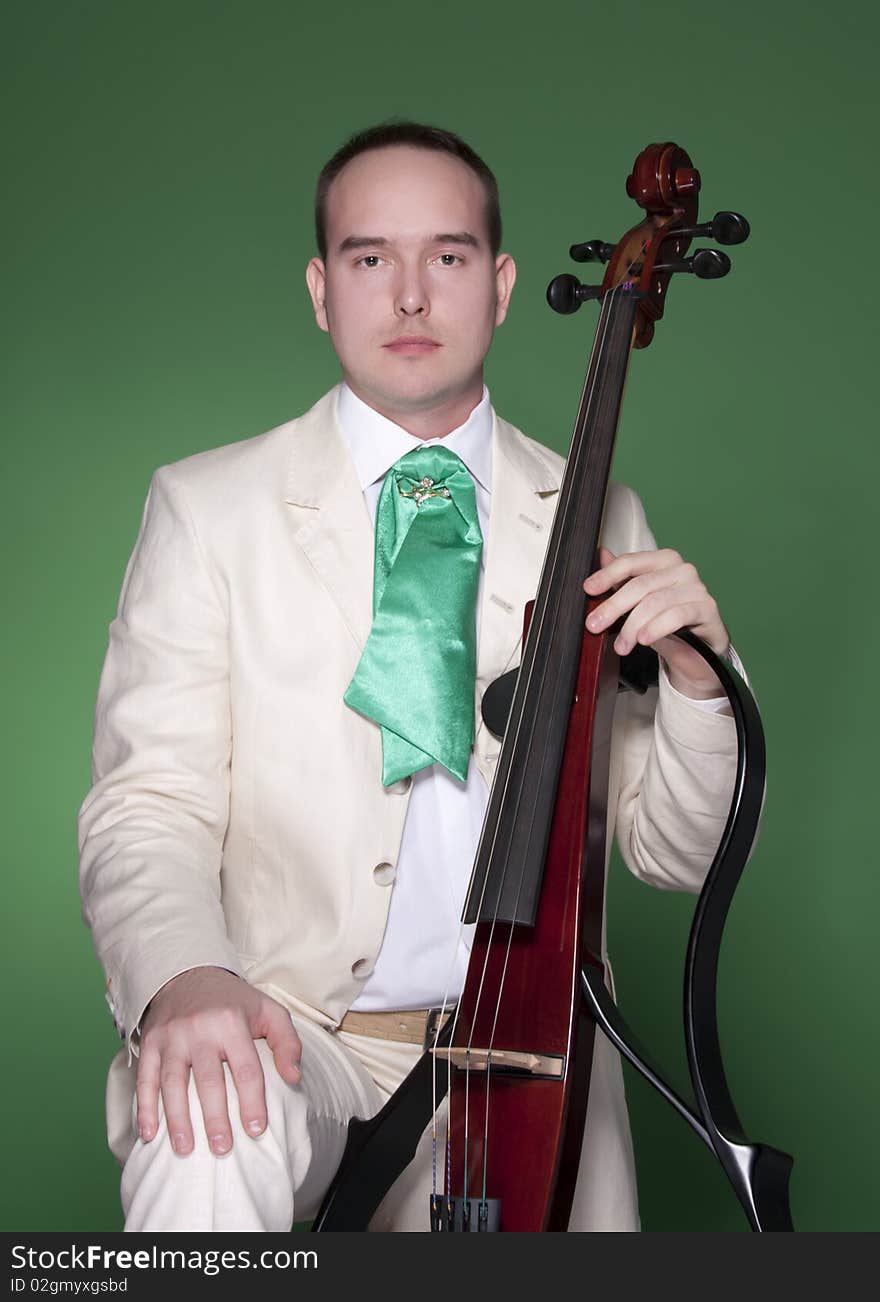 Portrait of young man with electic cello on green background. Portrait of young man with electic cello on green background