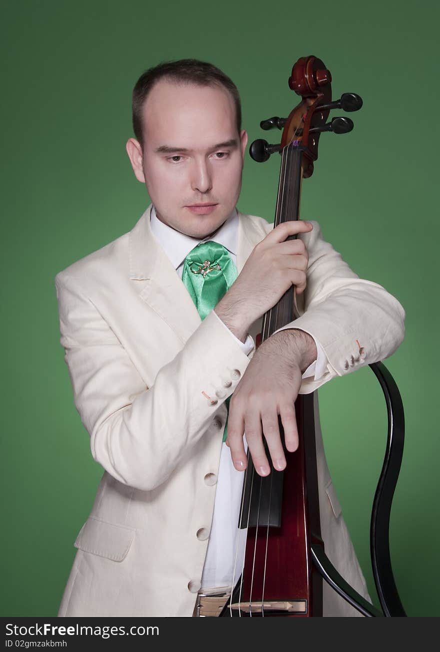 Portrait of young man with electic cello on green background. Portrait of young man with electic cello on green background