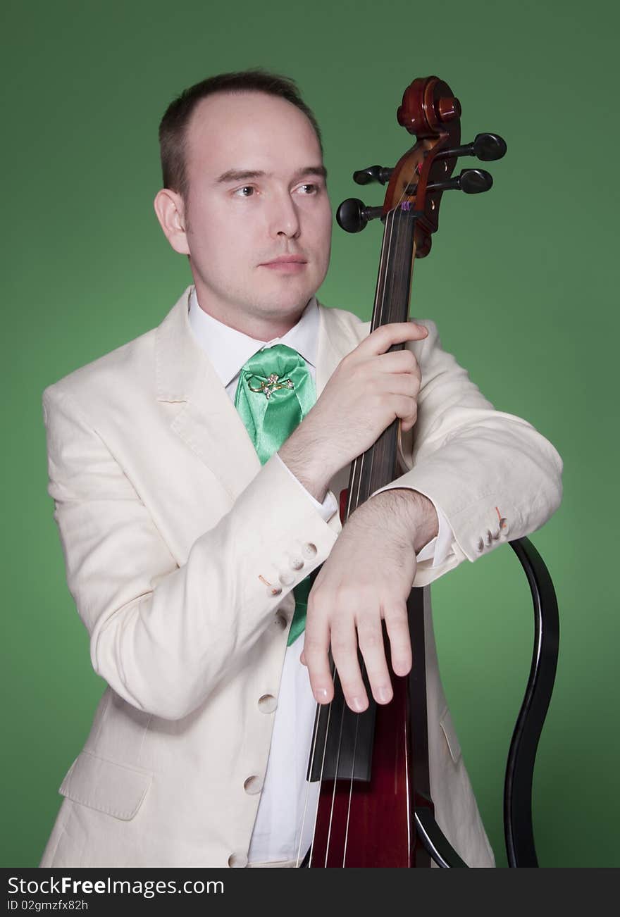 Portrait of young man with electic cello on green background. Portrait of young man with electic cello on green background