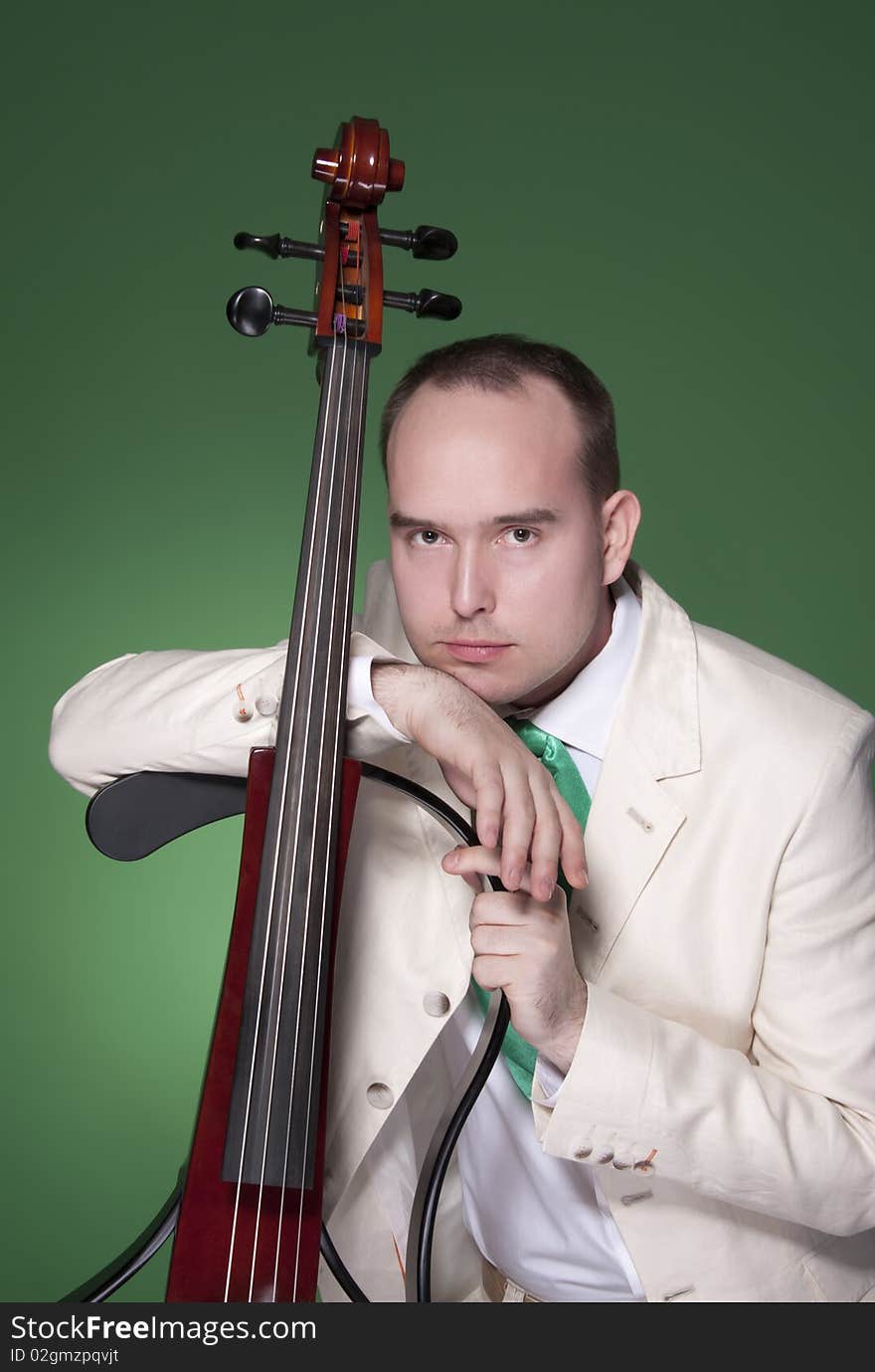 Portrait of young man with electic cello on green background. Portrait of young man with electic cello on green background