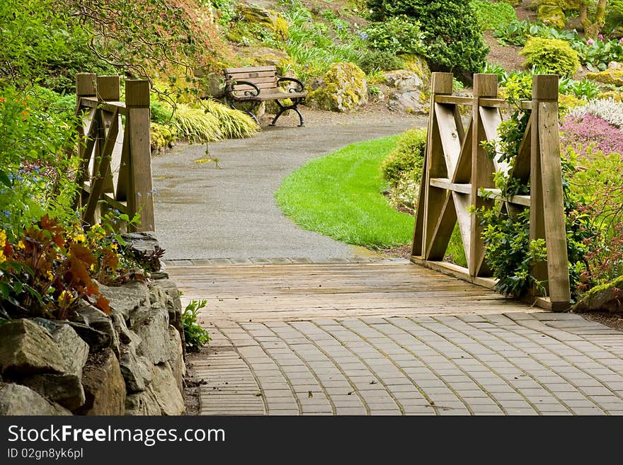 A curved garden pathway crosses a small bridge