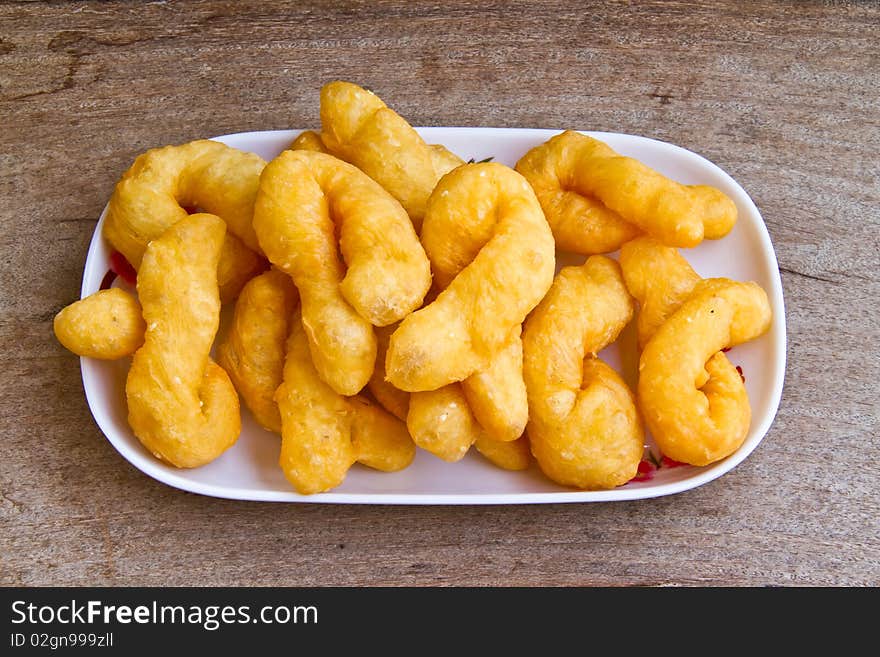 Chinese doughnuts in a white plate on wood table.