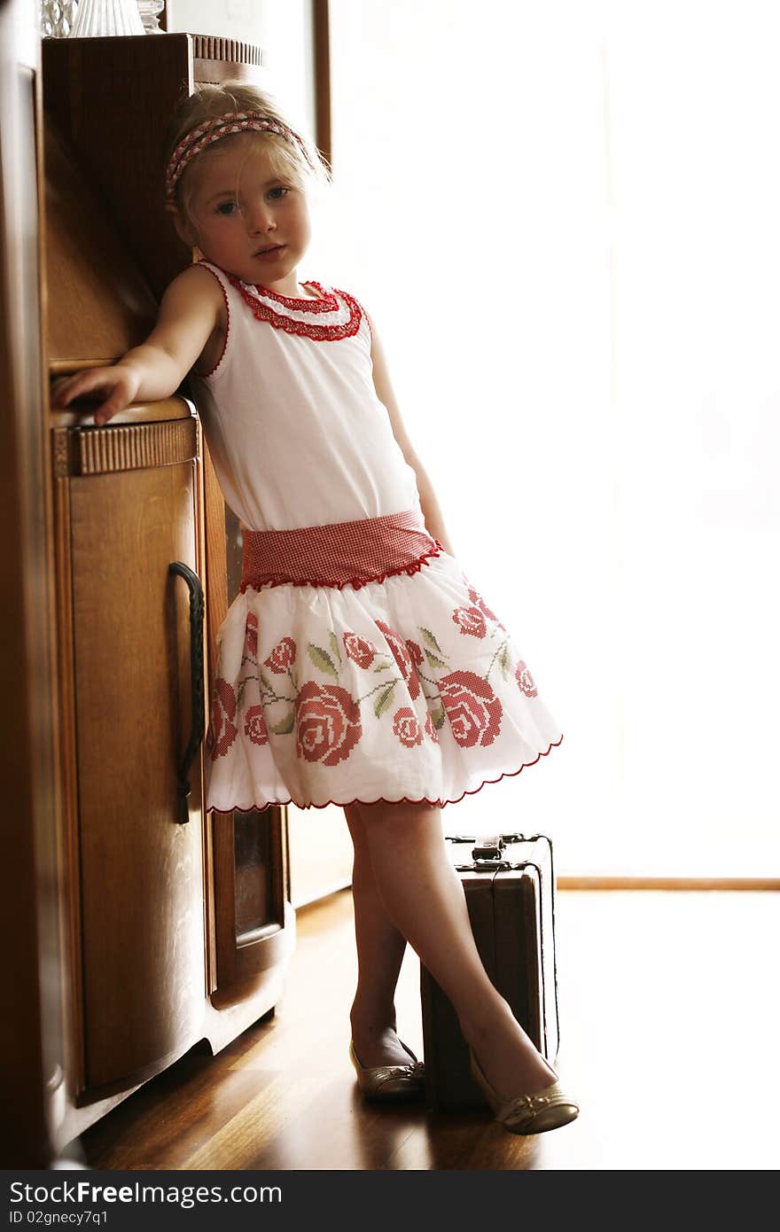 Little blonde girl waiting at front door ready to go on trip with suitcase in hand. Little blonde girl waiting at front door ready to go on trip with suitcase in hand.