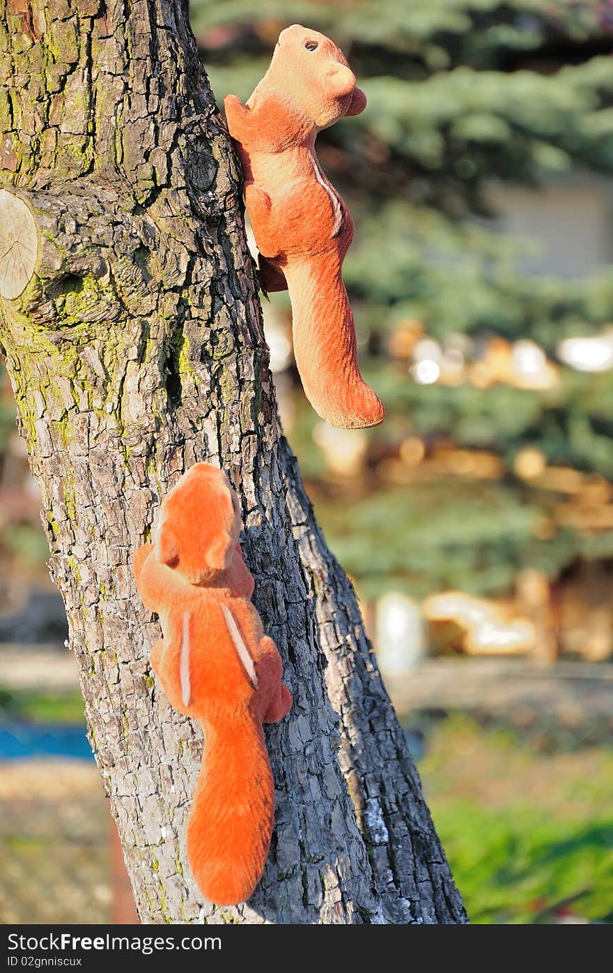 Picture shows a garden decorations. Two artificial squirrel clinging to a tree