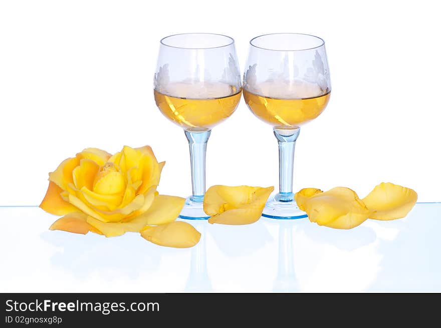 Two tumblers with white wine and yellow rose on the party. Two tumblers with white wine and yellow rose on the party