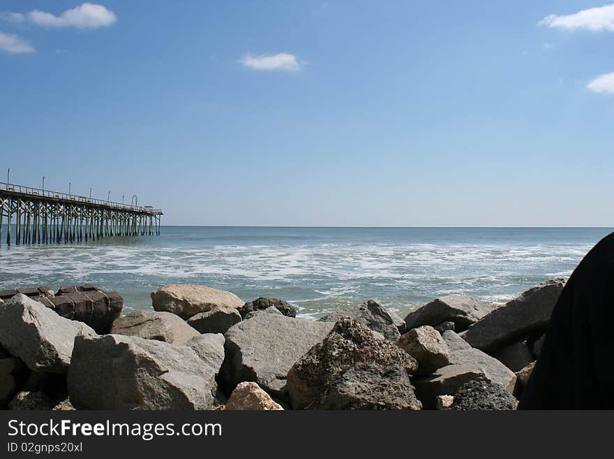 Beach scene with boulders and a pier. Beach scene with boulders and a pier