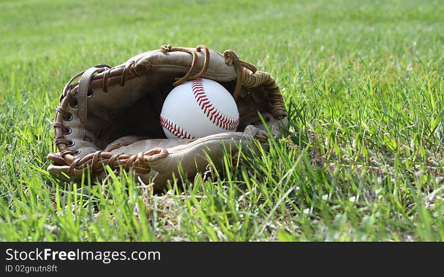 Baseball glove and ball on grass field. Baseball glove and ball on grass field.