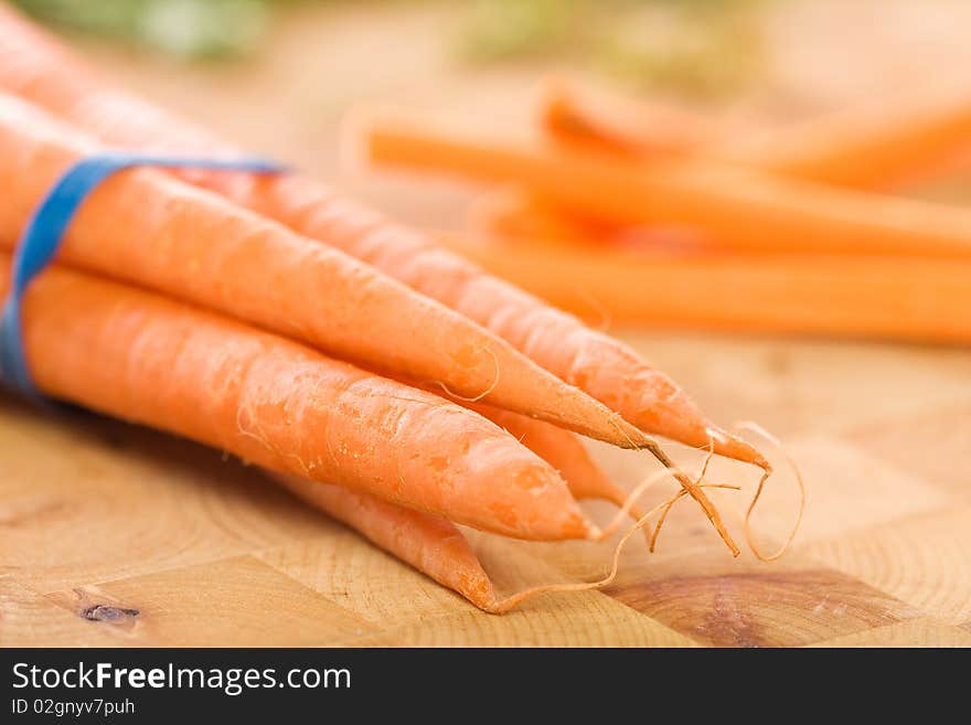 Carrots with green tops in bunch accompanied by carrot sticks