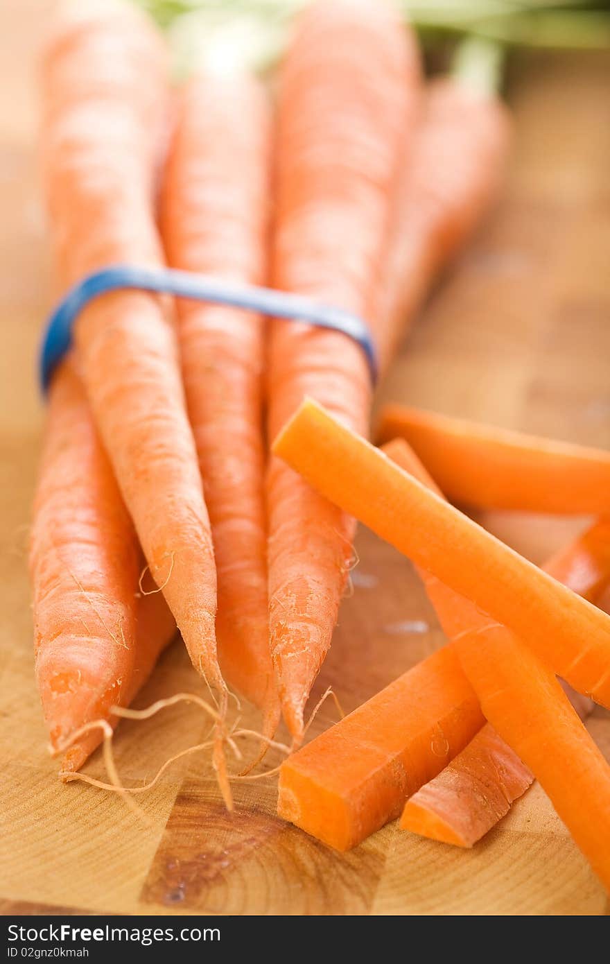 Carrots with green tops in bunch accompanied by carrot sticks