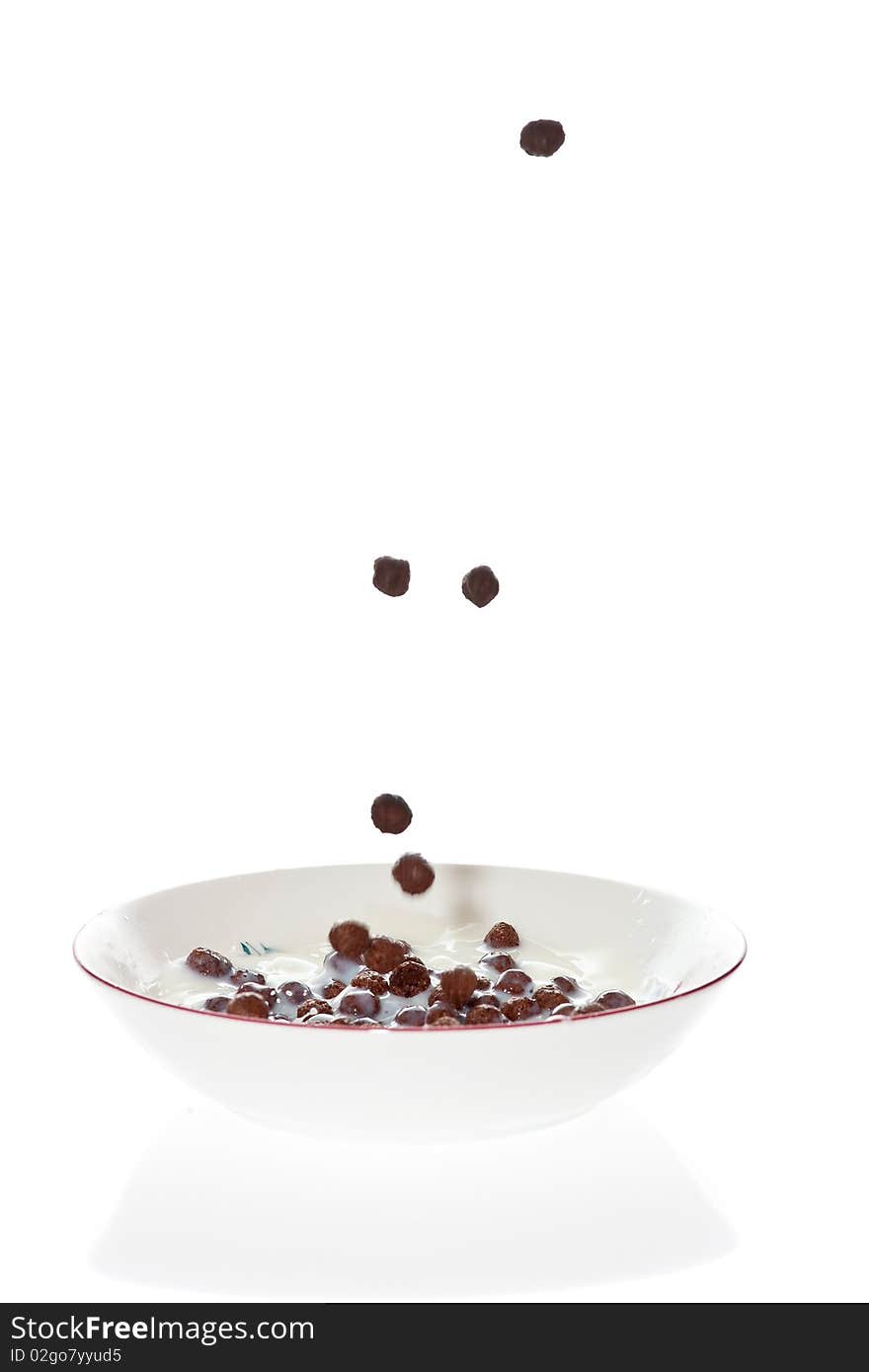 Chocolate cereal falling into a bowl of milk