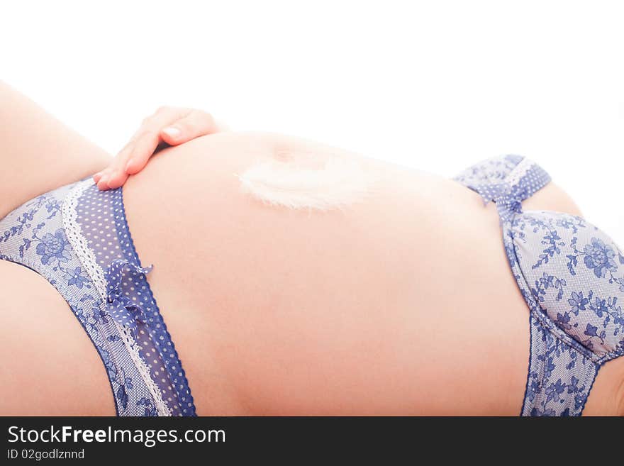 Bird feather lying on pregnant belly on white