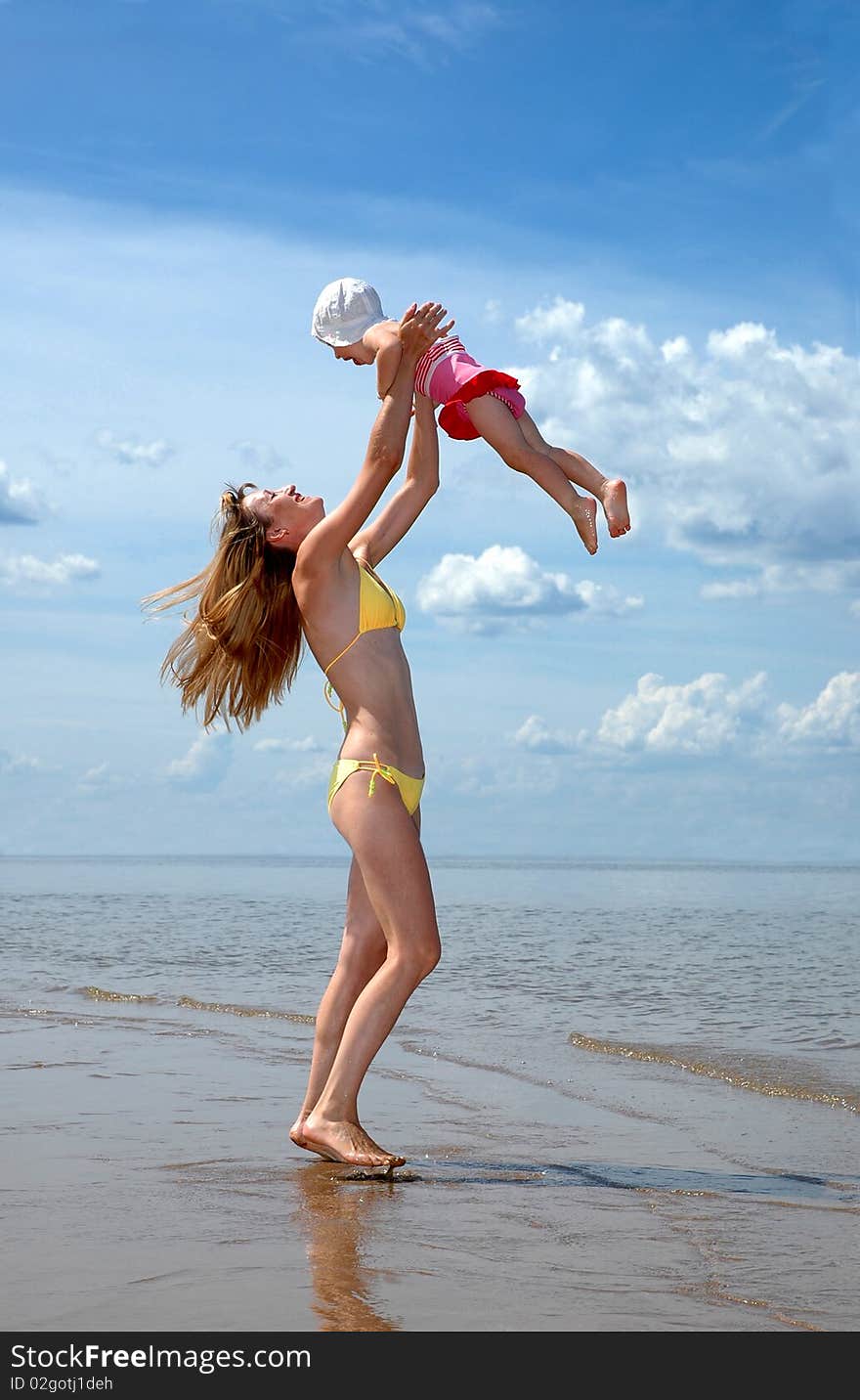 Young happy mother and baby on a beach