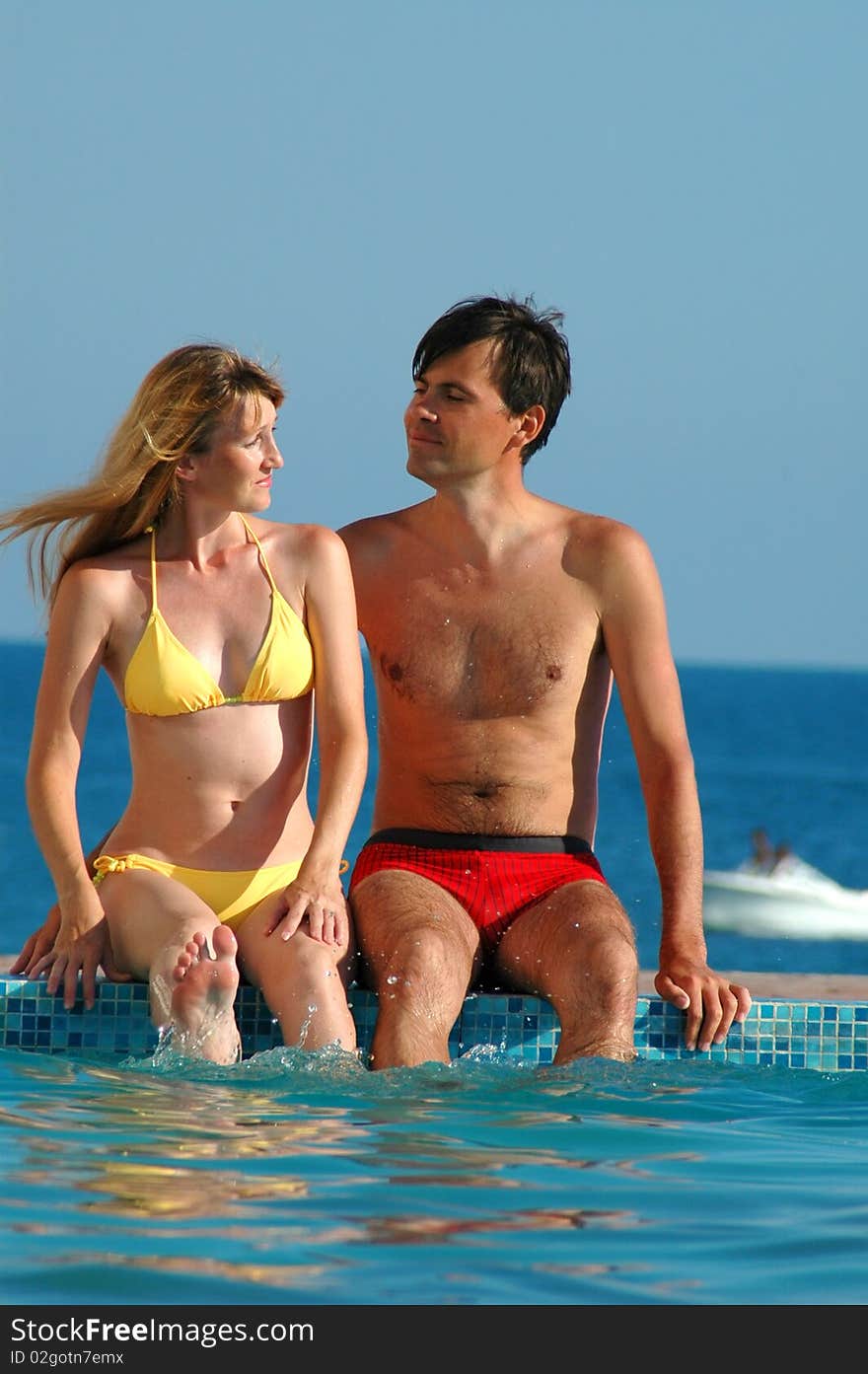 Man And Woman Sits Beside Water Pool