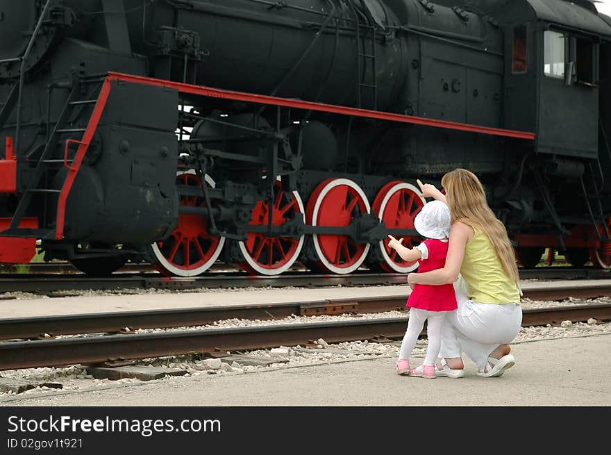 Woman with child look at old locomotive