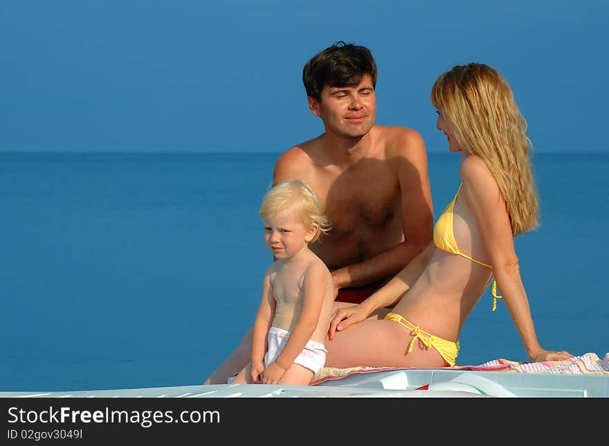 Young parents with the child sit on a beach