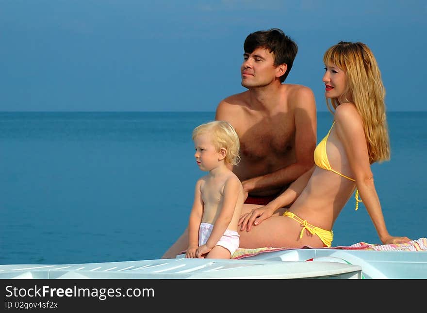 Young parents with the child sit on a beach